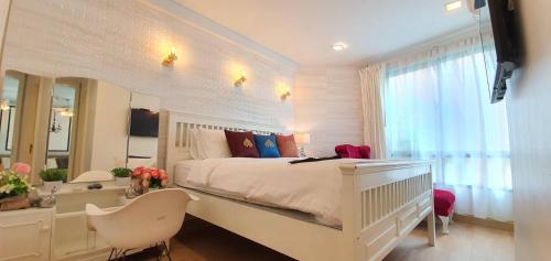 een witte slaapkamer met een wit bed en een spiegel bij marrakesh มาราเกซ หัวหิน in Hua Hin