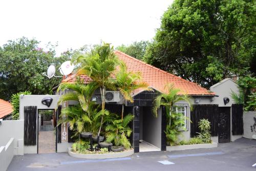 a house with palm trees in front of it at Laletsa Lodge in Durban