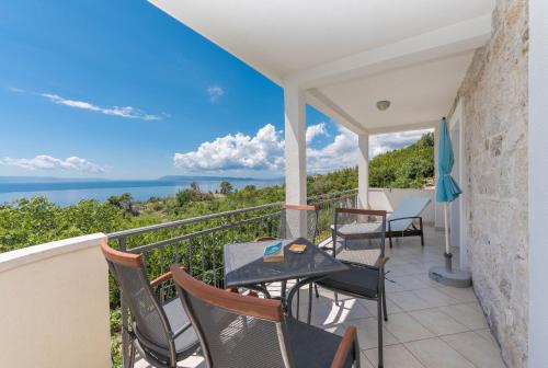 a balcony with chairs and tables and a view of the ocean at Vila Divna in Podgora