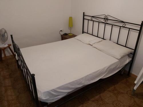 una camera da letto con un letto con lenzuola bianche e una lampada di monolocale per le vacanze a Peschici