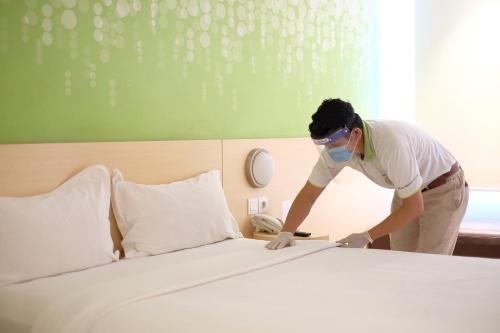 a man wearing a mask making a bed at Zest Harbour Bay Batam by Swiss-Belhotel International in Nagoya