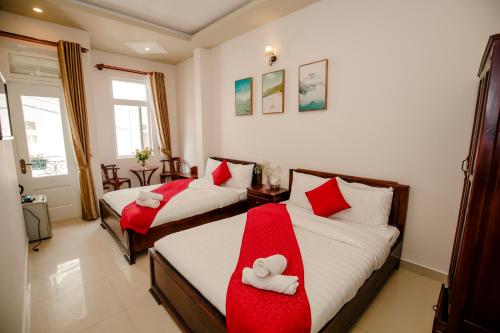 2 posti letto in una camera con asciugamani rossi e bianchi di Conico Đà Lạt Hotel a Da Lat