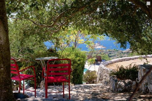 two red chairs and a table under a tree at Stone Cottages in Khalikerí