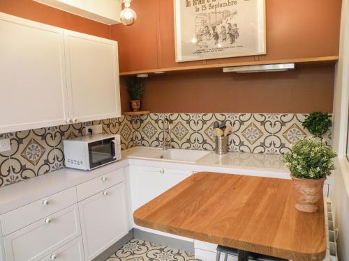 eine Küche mit weißen Schränken und einem Holztisch in der Unterkunft Le Petit Canut - Lyon Centre avec Terrasse - Majord'Home in Lyon
