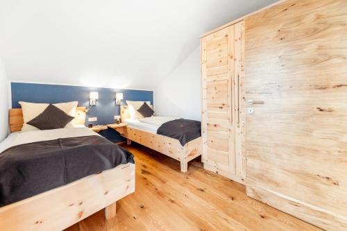 a bedroom with two beds and a wooden wall at Kärnten Apartment Turnersee in Sankt Kanzian