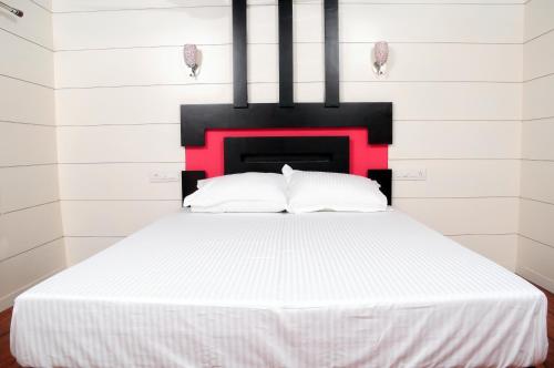 a bedroom with a white bed with a red headboard at Vaishnav Tours in Alleppey