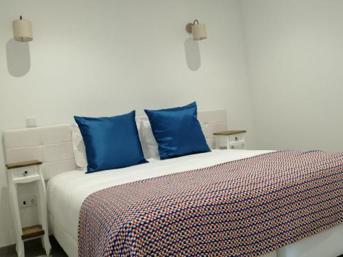 a bedroom with a bed with blue pillows at Raiz Alentejana in Reguengos de Monsaraz