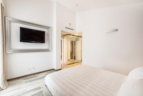 a white bedroom with a bed and a tv on the wall at Hotel Stella Della Versilia in Marina di Massa