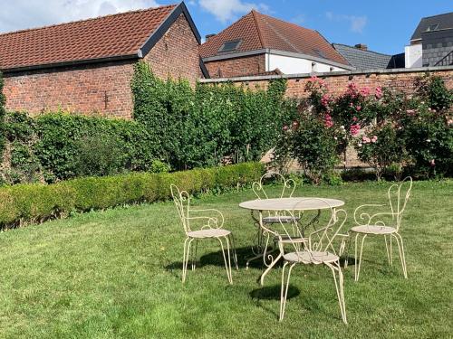 a table and chairs sitting in the grass at Villa Theresa à 25 min de PAIRI DAIZA in Soignies