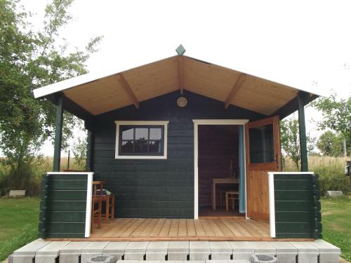 a black cabin with a porch and a wooden deck at Camping & Guest House Pliskovice in Mirovice