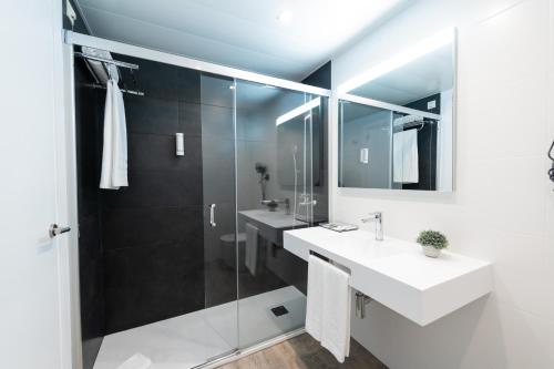 a bathroom with two sinks and a glass shower at Aparthotel Atenea Barcelona in Barcelona