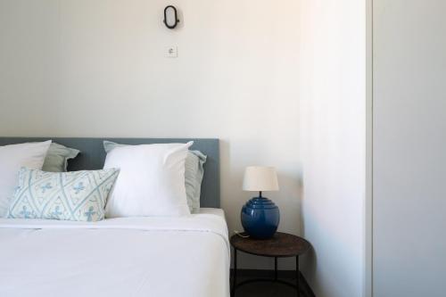 a bed with white sheets and a blue lamp on a table at Pink Flamingo Boutique Hostel in The Hague