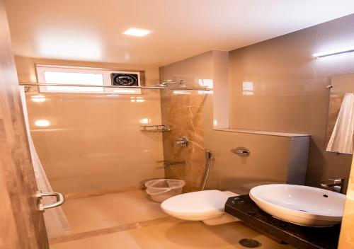 a bathroom with a shower and a toilet and a sink at Hotel Prabha Palace in Ahmadnagar