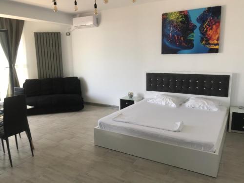 ein Schlafzimmer mit einem weißen Bett und einem Sofa in der Unterkunft Alezzi Sunwaves in Mamaia Nord – Năvodari