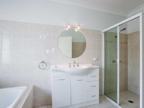 a white bathroom with a sink and a mirror at 2 137 Soldiers Point Road luxury unit on the waterfront with aircon and free unlimited WiFi in Salamander Bay