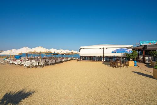 a beach with tables and chairs and umbrellas at Playa and Chill in San Juan de los Terreros