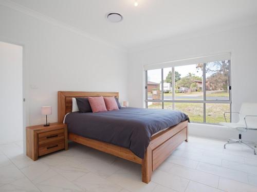 a bedroom with a bed and a large window at 5b Bent Street large house with ducted air con foxtel and wifi in Fingal Bay