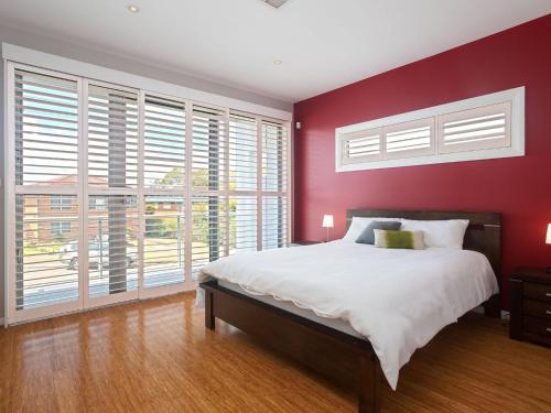 Schlafzimmer mit roten Wänden und einem Bett mit weißer Bettwäsche in der Unterkunft 7 Judith Street Stunning duplex with ducted air in Corlette