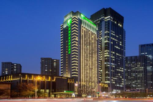 天津的住宿－天津融僑套房假日酒店，一座高大的建筑,上面有绿灯
