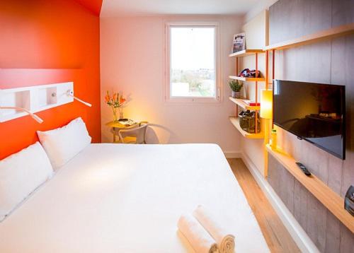 a bedroom with a white bed and a flat screen tv at ibis budget Beauvais Aeroport in Beauvais