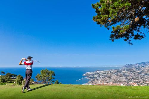 a man playing golf on a hill with a view of the ocean at Casa Velha do Palheiro Relais & Chateaux in Funchal