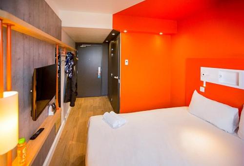 a hotel room with a large bed and a television at ibis budget Beauvais Aeroport in Beauvais