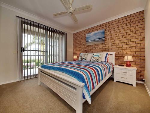 a bedroom with a bed and a brick wall at Bushmans, 9 24 Tomaree Street - Spacious townhouse with air conditioning and close to Nelson Bay Town Centre in Nelson Bay