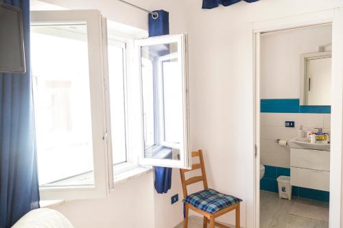 a small bedroom with a window and a chair at Bilocale sul lungomare di Forio d'Ischia - Serpico sea & more in Ischia