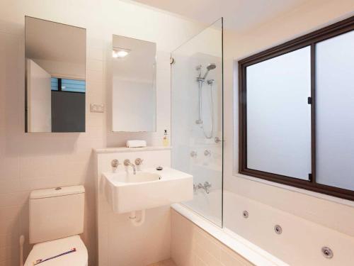 a bathroom with a sink and a toilet and a mirror at Beach House 7 26 One Mile Close air conditioned wifi foxtel linen in Anna Bay