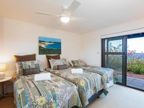 ein Schlafzimmer mit zwei Betten und einem Fenster in der Unterkunft Beach House 7 26 One Mile Close air conditioned wifi foxtel linen in Anna Bay