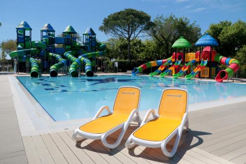 a swimming pool with two chairs in front of a water park at Casa mobile Gustocamp a Cavallino Treporti in Cavallino-Treporti