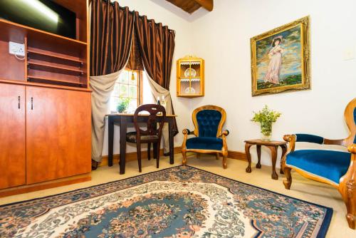 a living room with chairs and a table and a rug at Melkboomsdrift Guest House & Conference Centre in Vredendal