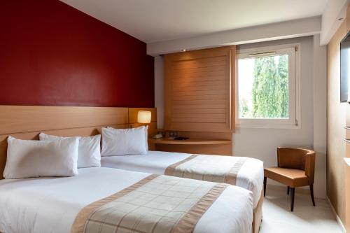 a hotel room with two beds and a window at Best Western Plus Le Lavarin in Avignon