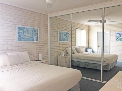 a bedroom with two beds and a mirror at Classic View 1, 1 49 Victoria Parade - panoramic water views, aircon and Wifi in Nelson Bay