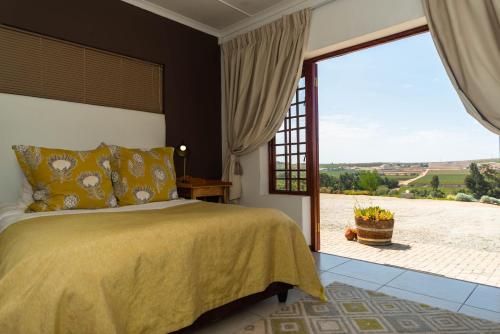 a bedroom with a bed and a large window at Melkboomsdrift Guest House & Conference Centre in Vredendal