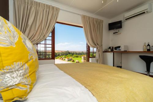 a bedroom with a large bed with a large window at Melkboomsdrift Guest House & Conference Centre in Vredendal