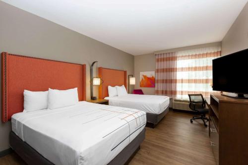 a hotel room with two beds and a flat screen tv at La Quinta by Wyndham Altoona Des Moines in Altoona
