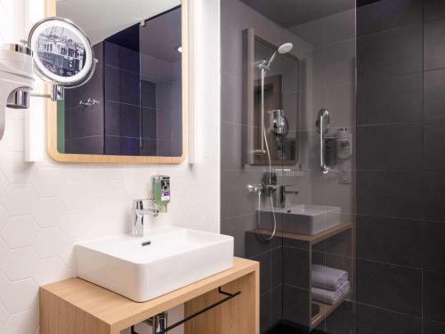 a bathroom with a sink and a mirror and a shower at Mercure Warszawa Ursus Station in Warsaw