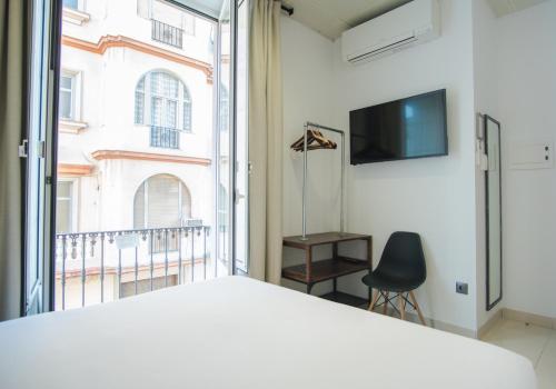 a bedroom with a bed and a large window at The Lights Hostel in Málaga