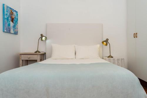 a bedroom with a large white bed with two lamps at Melkboomsdrift Guest House & Conference Centre in Vredendal