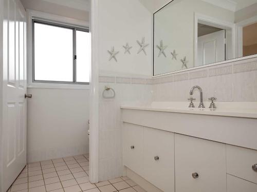 a white bathroom with a sink and a mirror at Bushmans, 9 24 Tomaree Street - Spacious townhouse with air conditioning and close to Nelson Bay Town Centre in Nelson Bay