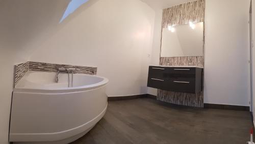une salle de bain avec une baignoire, un lavabo et un miroir dans l'établissement Agréable maison moderne, à Le Hézo