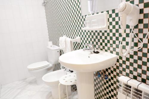 a white bathroom with a sink and a toilet at Hotel Andalucia in Lanjarón