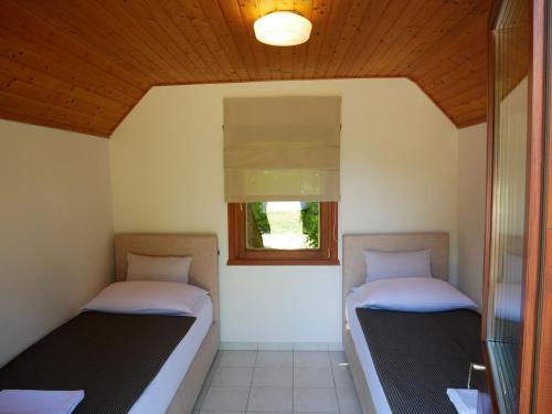 two beds in a room with a window at Bungalows Korana - Campsite Korana in Seliste Dreznicko