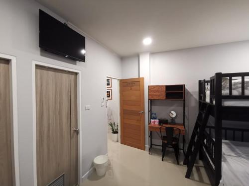 ein Schlafzimmer mit einem Etagenbett und einem Schreibtisch mit einem TV in der Unterkunft DAAD FAH home and cafe in Phetchaburi