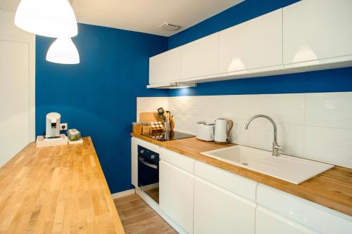 eine Küche mit weißen Schränken und einer blauen Wand in der Unterkunft Les Douces Breizh - Jules Ferry - Proximité Gare SNCF in Saint-Brieuc