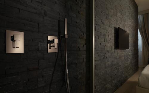a bathroom with a brick wall with pictures on it at LE RÊVE DE NAIM Roma in Rome
