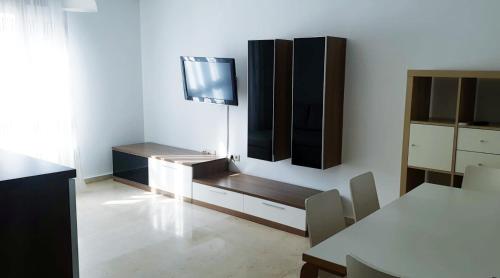 uma sala de estar com uma mesa e uma televisão na parede em Beatiful and full-equipped flat in the city center em Ceuta