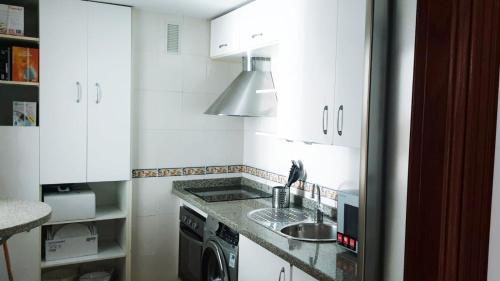 cocina blanca con fregadero y fogones en Beatiful and full-equipped flat in the city center en Ceuta