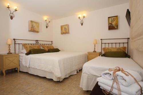 two beds in a room with white walls and lamps at Villa Isabella in Naousa